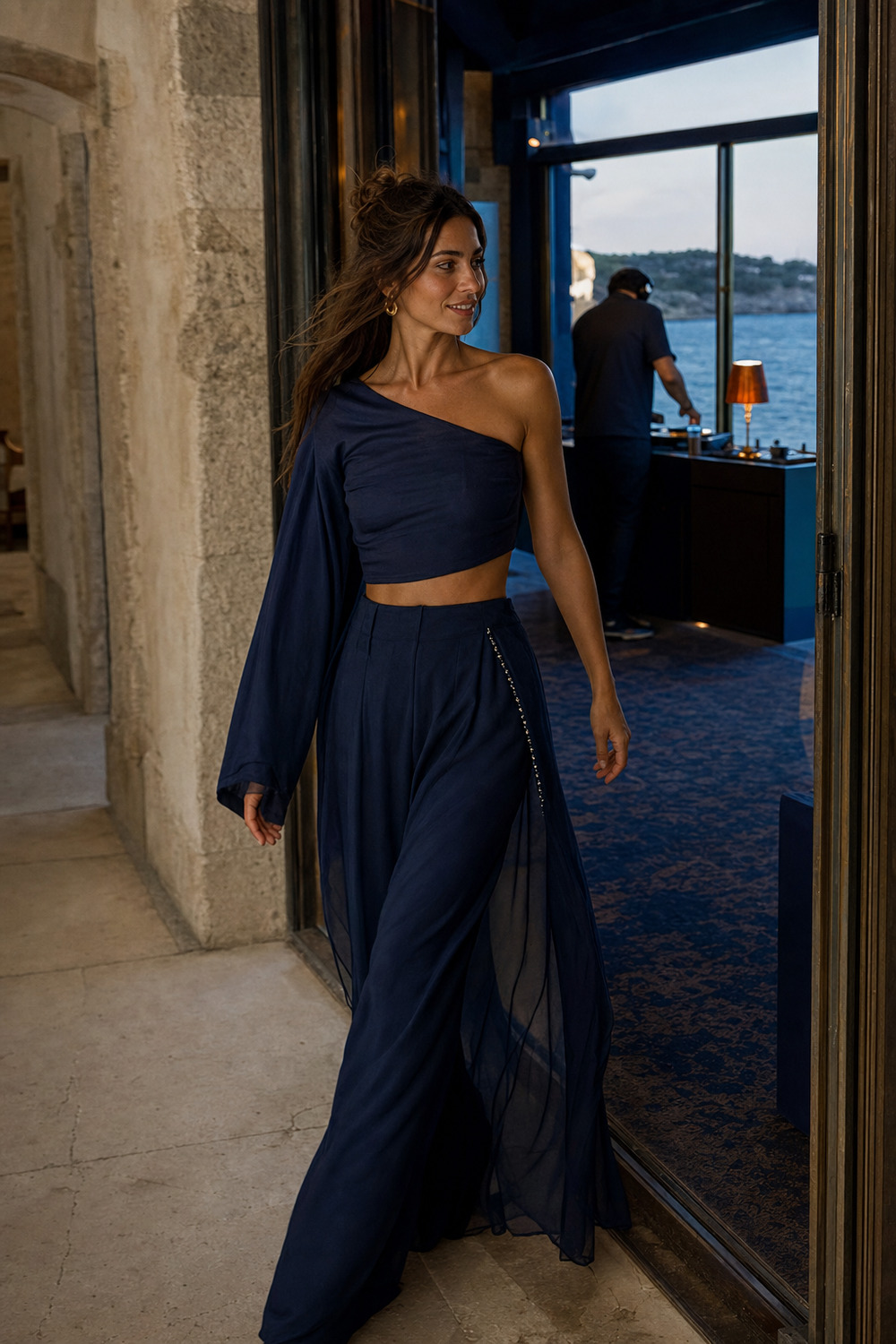 A woman in a cobalt two-piece walking into a listening room.